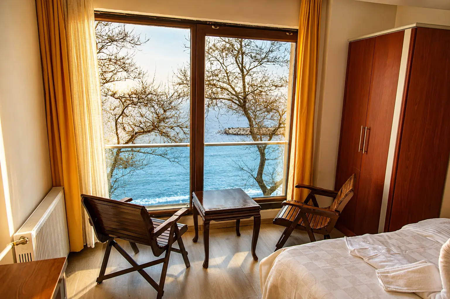 Zimmer mit Meerblick: zwei Holzstühle und ein kleiner Tisch vor einem breiten Fenster
