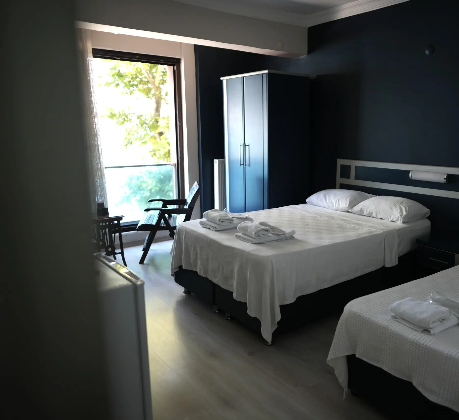 Zimmer für drei: dunkelblaue Wand, ein Doppel- und ein Einzelbett, Balkontür